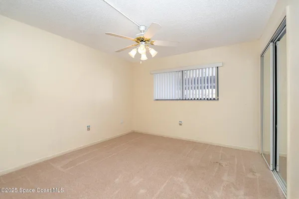 an empty room with a window and a fan