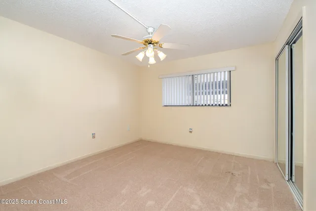 an empty room with a window and a fan