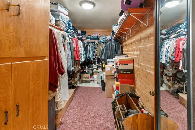 a view of walk in closet with clothes shoes and a rug