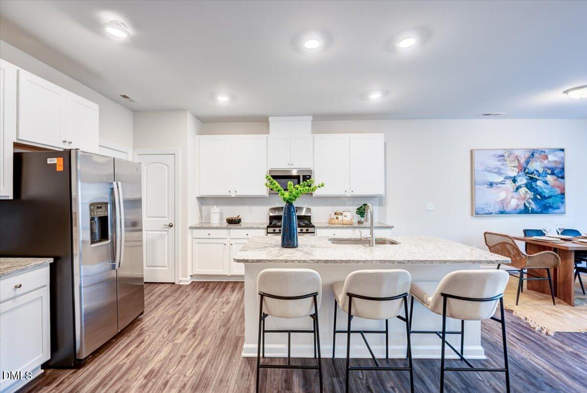 1209 Alston Ridge Cary, NC 27519 - Photo 4 of 27 a kitchen with stainless steel appliances granite countertop a dining table chairs stove refrigerator and cabinets