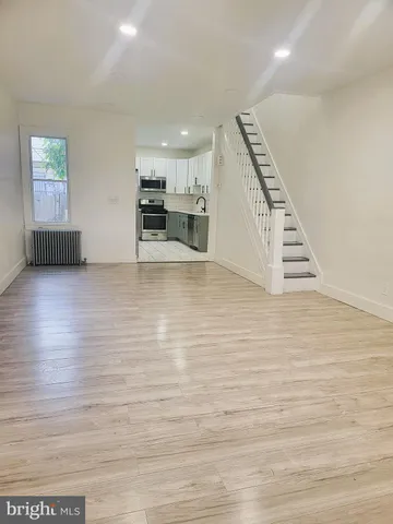 a view of kitchen and empty room with wooden floor