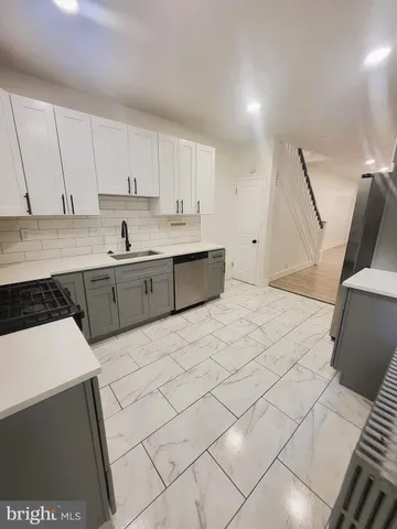 a large white kitchen with sink and cabinets