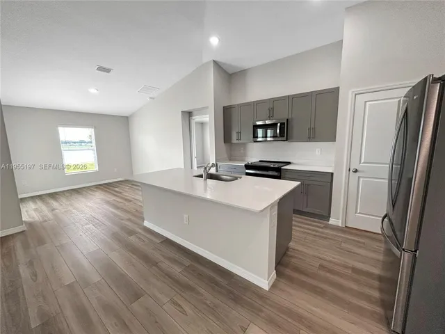 a kitchen with stainless steel appliances granite countertop a sink a stove a refrigerator and cabinets