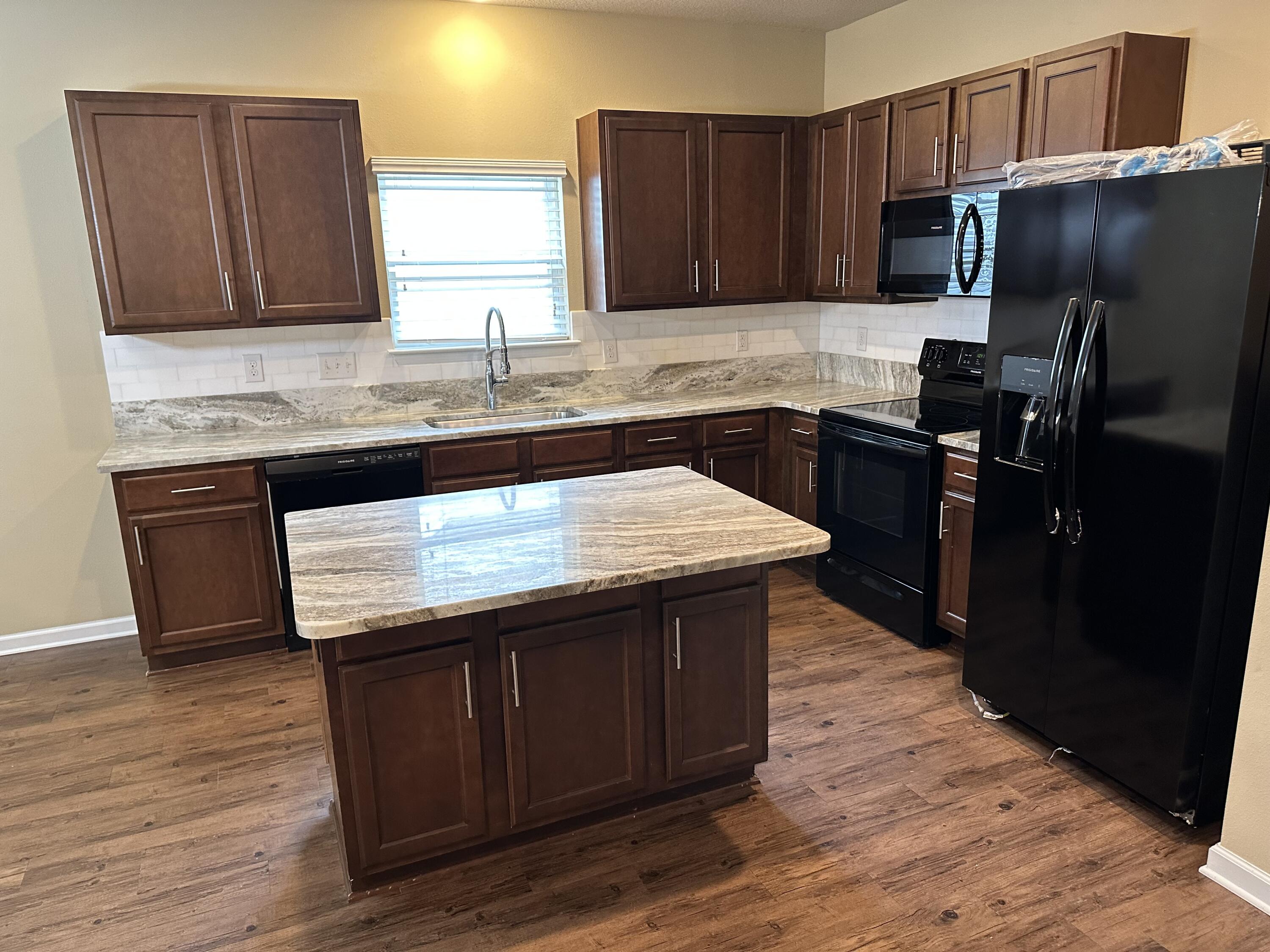 260 Cornelia Street Freeport, FL 32439 - Photo 7 of 31 a kitchen with granite countertop wooden cabinets a refrigerator and a sink