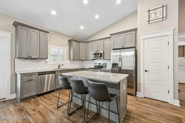 a kitchen with kitchen island granite countertop wooden floors and white cabinets