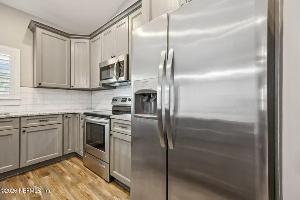 a kitchen with stainless steel appliances kitchen island granite countertop a refrigerator a stove a microwave oven with white cabinets