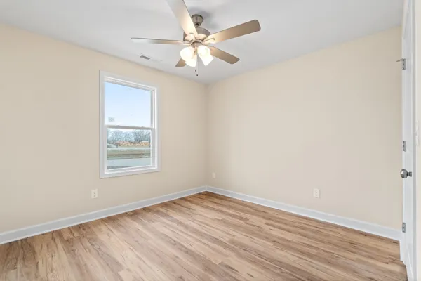 an empty room with wooden floor and windows