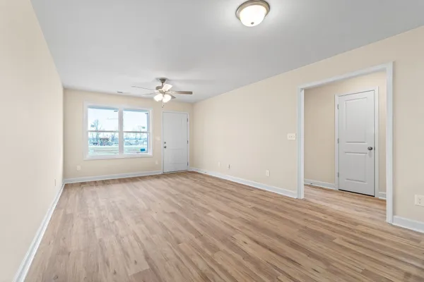 an empty room with wooden floor cabinet and windows