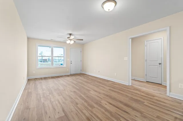 an empty room with wooden floor cabinet and windows