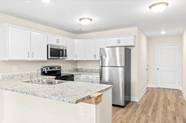 a kitchen with granite countertop a refrigerator a sink a stove a microwave and wooden floor