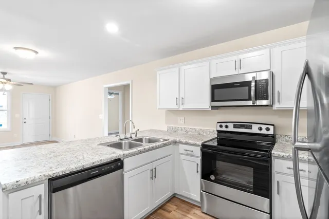a kitchen with stainless steel appliances granite countertop a sink dishwasher stove and microwave with wooden cabinets