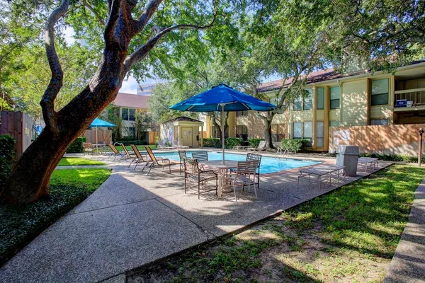 a view of backyard with swimming pool and table and chairs under an umbrella