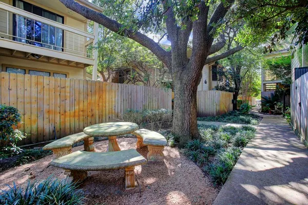 a backyard of a house with table and chairs plants and large tree