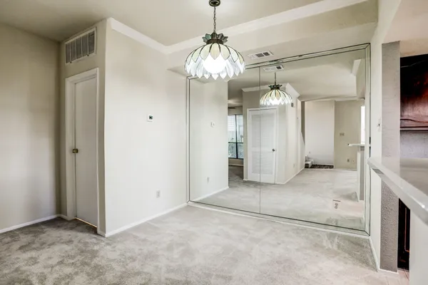 a view of a hallway with chandelier and refrigerator