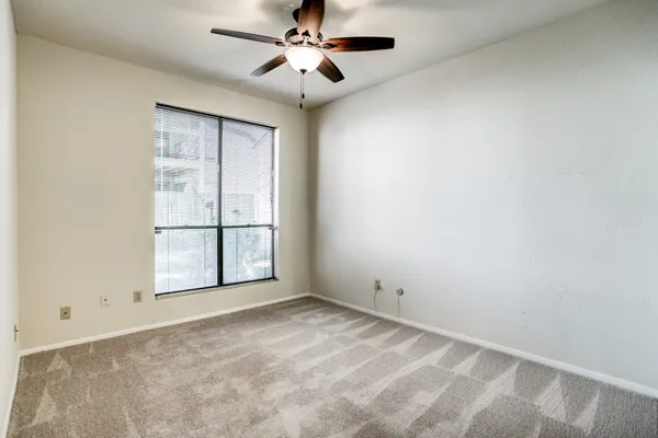 an empty room with windows and ceiling fan
