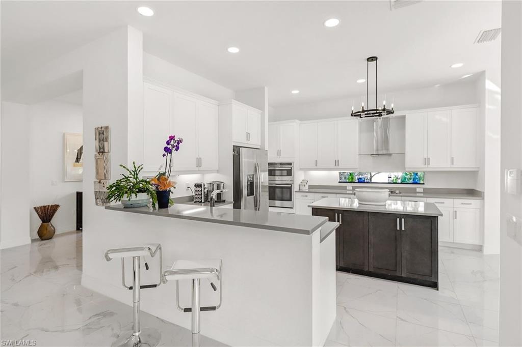 4617 Azalea Drive Naples, FL 34119 - Photo 7 of 34 a kitchen with stainless steel appliances kitchen island granite countertop a refrigerator and microwave