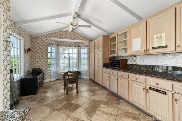 a large white kitchen with granite countertop a stove a sink a dining table and chairs next to a window