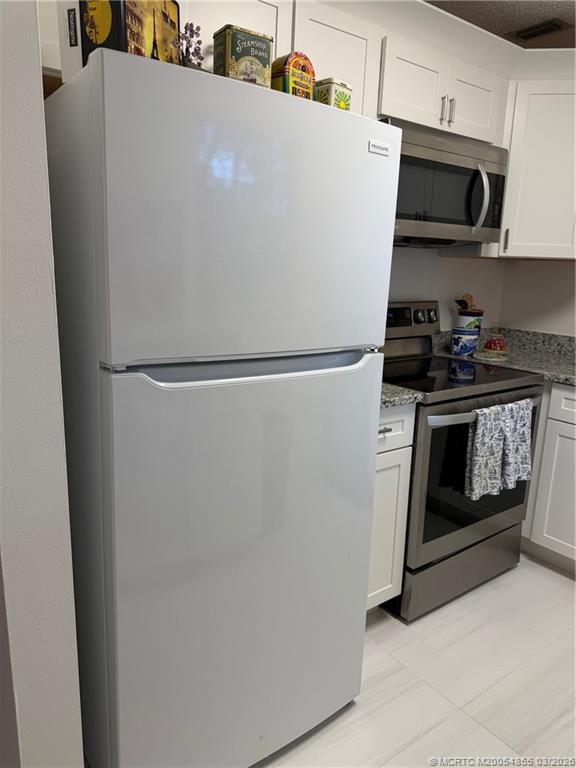 1225 Northwest 21st Street, Unit 7705 Stuart, FL 34994 - Photo 9 of 28 a white refrigerator freezer and a stove sitting inside of a kitchen