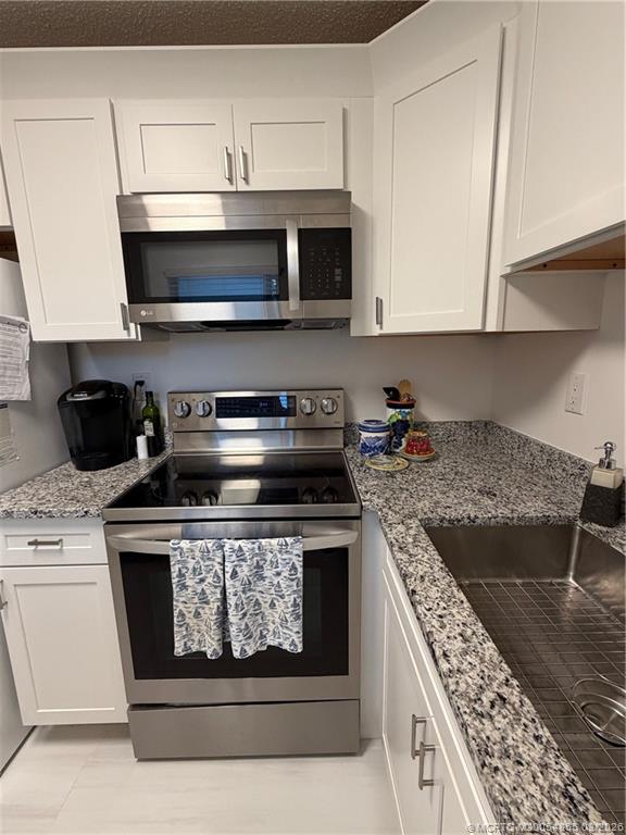 1225 Northwest 21st Street, Unit 7705 Stuart, FL 34994 - Photo 10 of 28 a kitchen with stainless steel appliances granite countertop a stove and a microwave