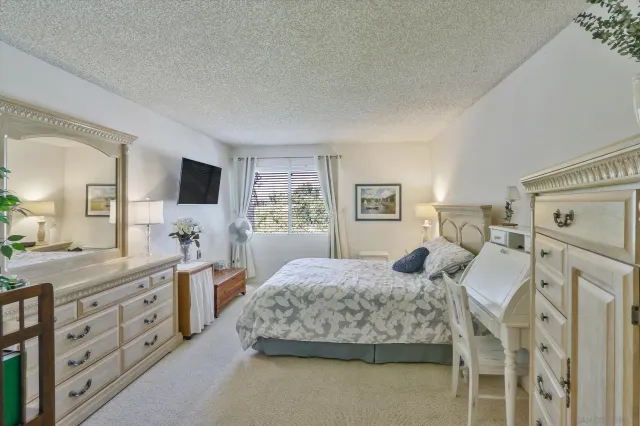 a bedroom with a large bed and a flat tv screen on dresser
