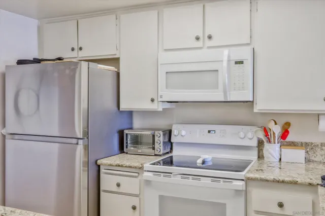 a kitchen with stainless steel appliances granite countertop a refrigerator sink and white cabinets