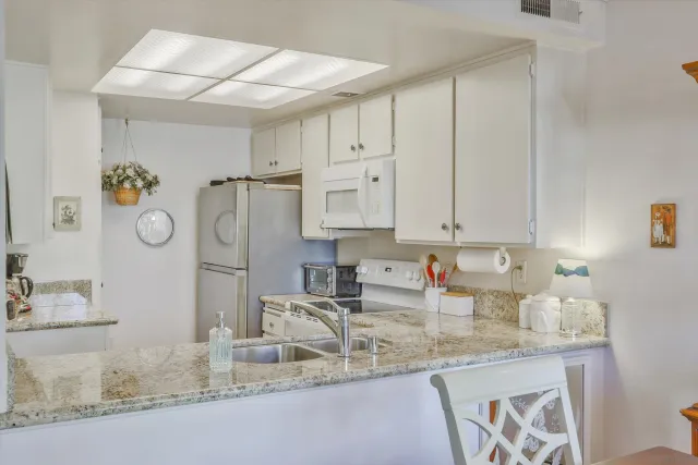 a kitchen with granite countertop a sink a stove and cabinets