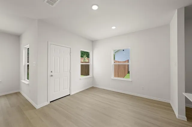 a view of an empty room with a window and wooden floor