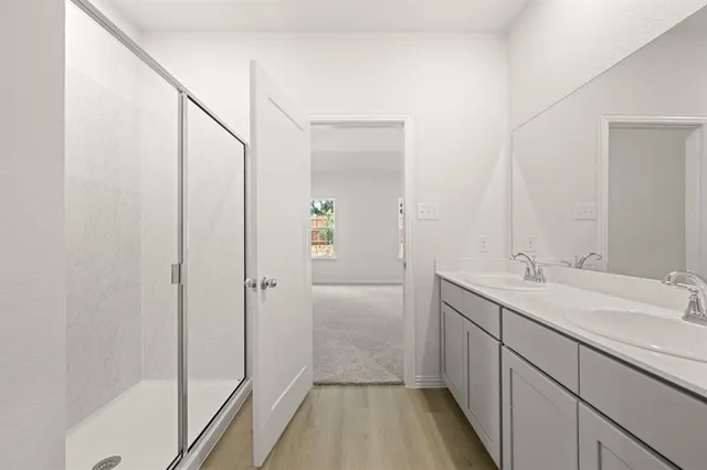 a bathroom with a sink and mirror with shower