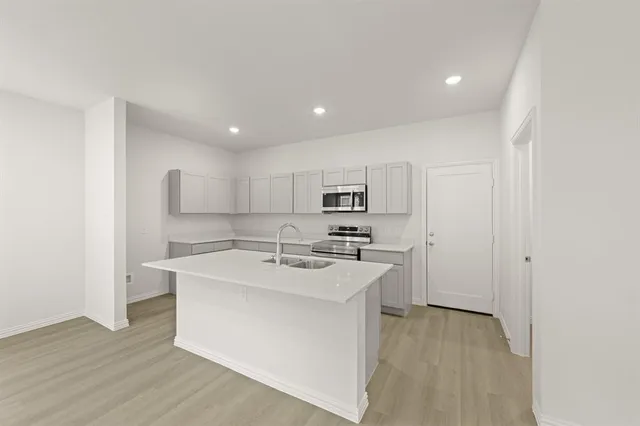 a large white kitchen with kitchen island a sink a stove a refrigerator and white cabinets