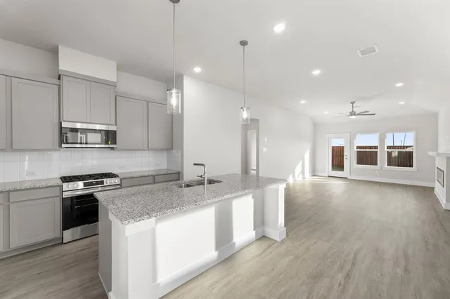 a kitchen with stainless steel appliances granite countertop a sink a stove and a wooden floors