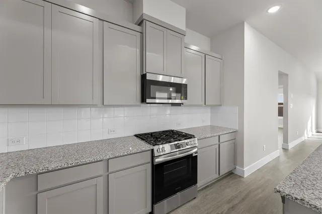 a kitchen with granite countertop white cabinets and stainless steel appliances