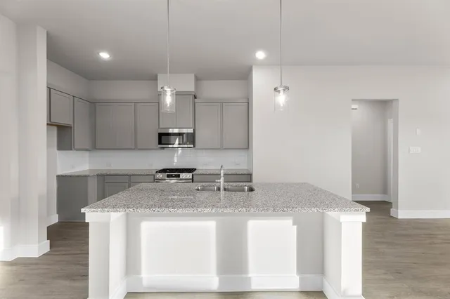 a kitchen with kitchen island granite countertop a sink a counter top space and cabinets