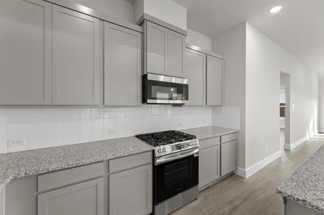 a kitchen with granite countertop white cabinets and stainless steel appliances