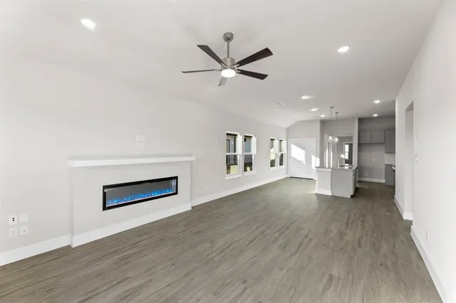 a view of a livingroom with a ceiling fan wooden floor and a ceiling fan