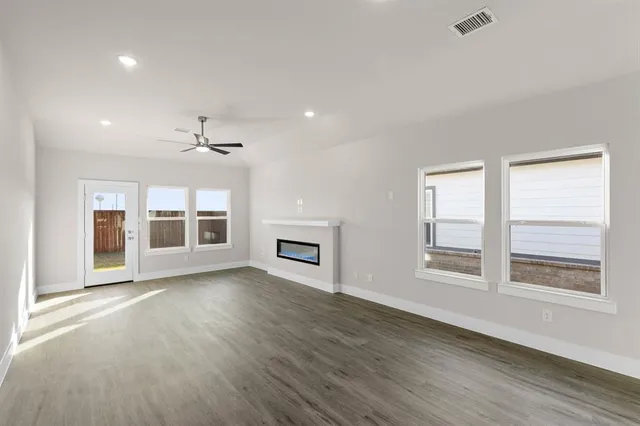 a view of an empty room with a window and wooden floor
