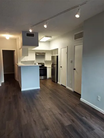 an open kitchen with a refrigerator and a stove top oven
