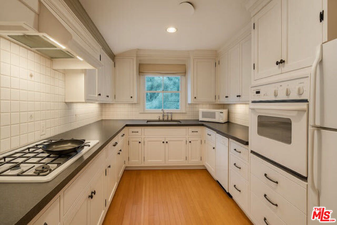 14807 Round Valley Drive Sherman Oaks, CA 91403 - Photo 6 of 25 a kitchen with granite countertop white cabinets and white appliances
