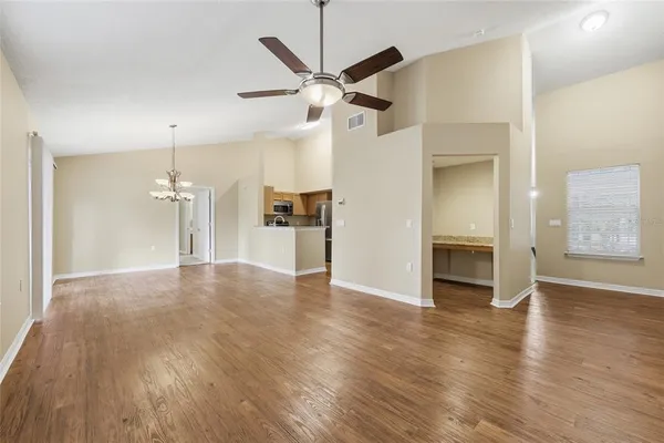 a view of empty room with wooden floor and ceiling fan