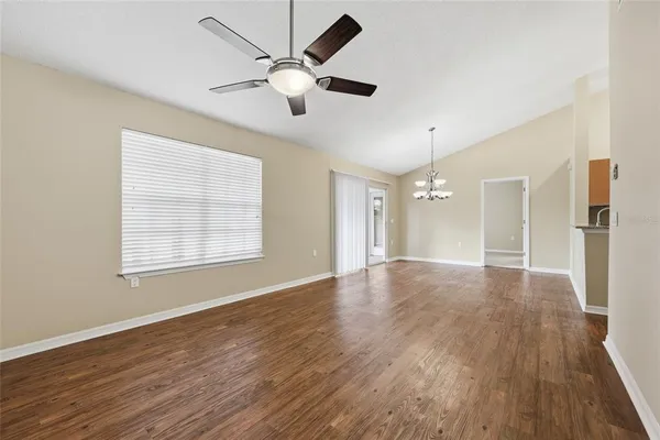 an empty room with wooden floor fan and windows