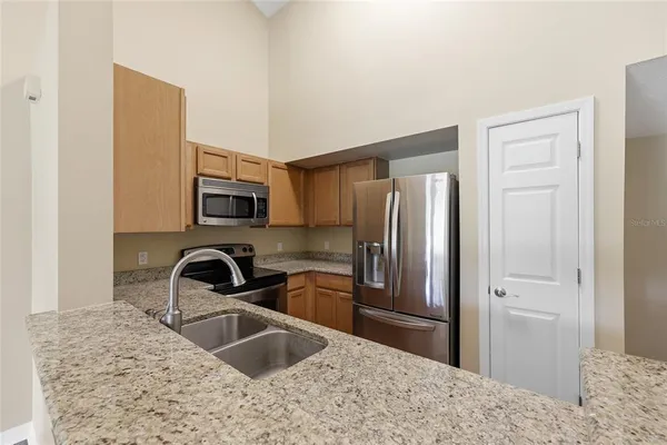 a kitchen with stainless steel appliances granite countertop a refrigerator a stove and a sink