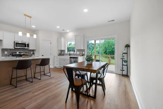 a dining room with wooden floor a chandelier a wooden table and chairs