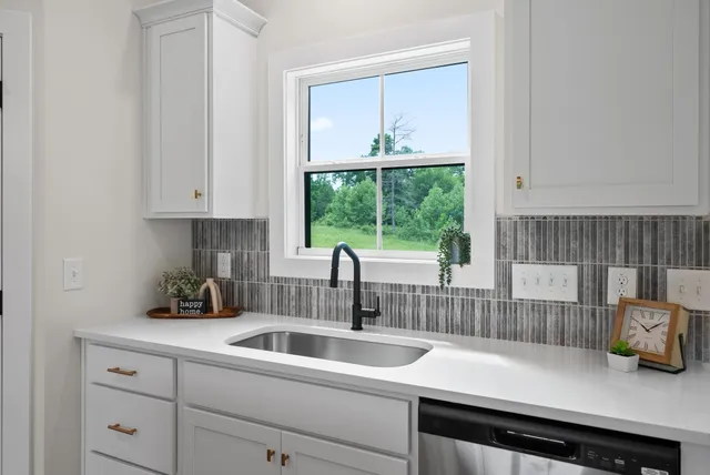 a kitchen with stainless steel appliances granite countertop a stove top oven a sink dishwasher a refrigerator and white cabinets with wooden floor