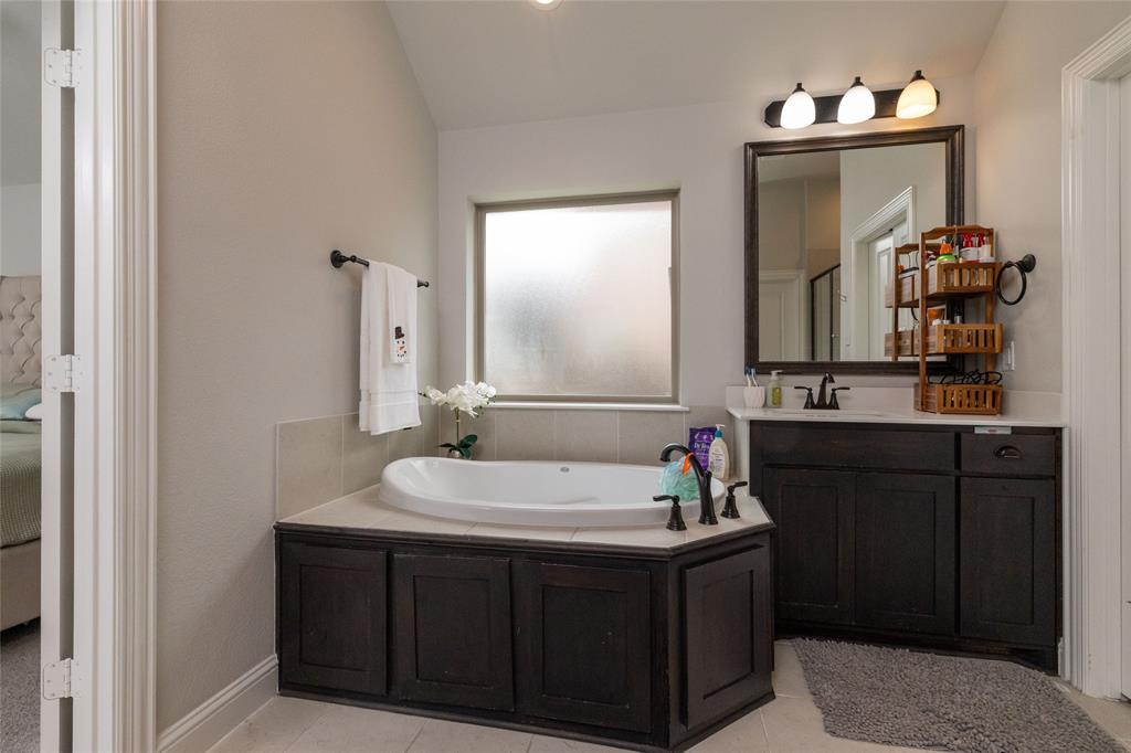 4045 Grove Valley Road Midlothian, TX 76065 - Photo 25 of 34 Bathroom featuring a garden tub, vanity, light tile patterned floors, and vaulted ceiling