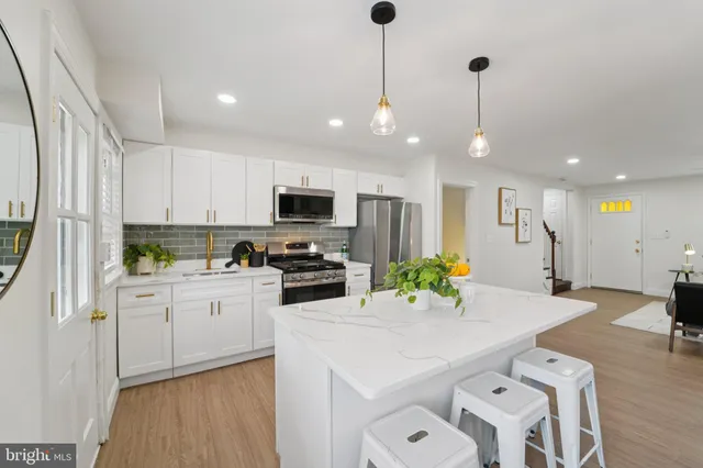 a kitchen with stainless steel appliances kitchen island granite countertop a sink a stove a refrigerator cabinets and living room view