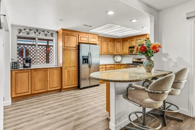 a kitchen with granite countertop a table chairs stove and wooden floor