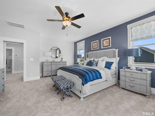 a spacious bedroom with a bed a chandelier and a mirror