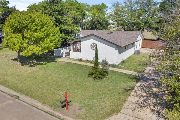 a backyard of a house with large trees and wooden fence