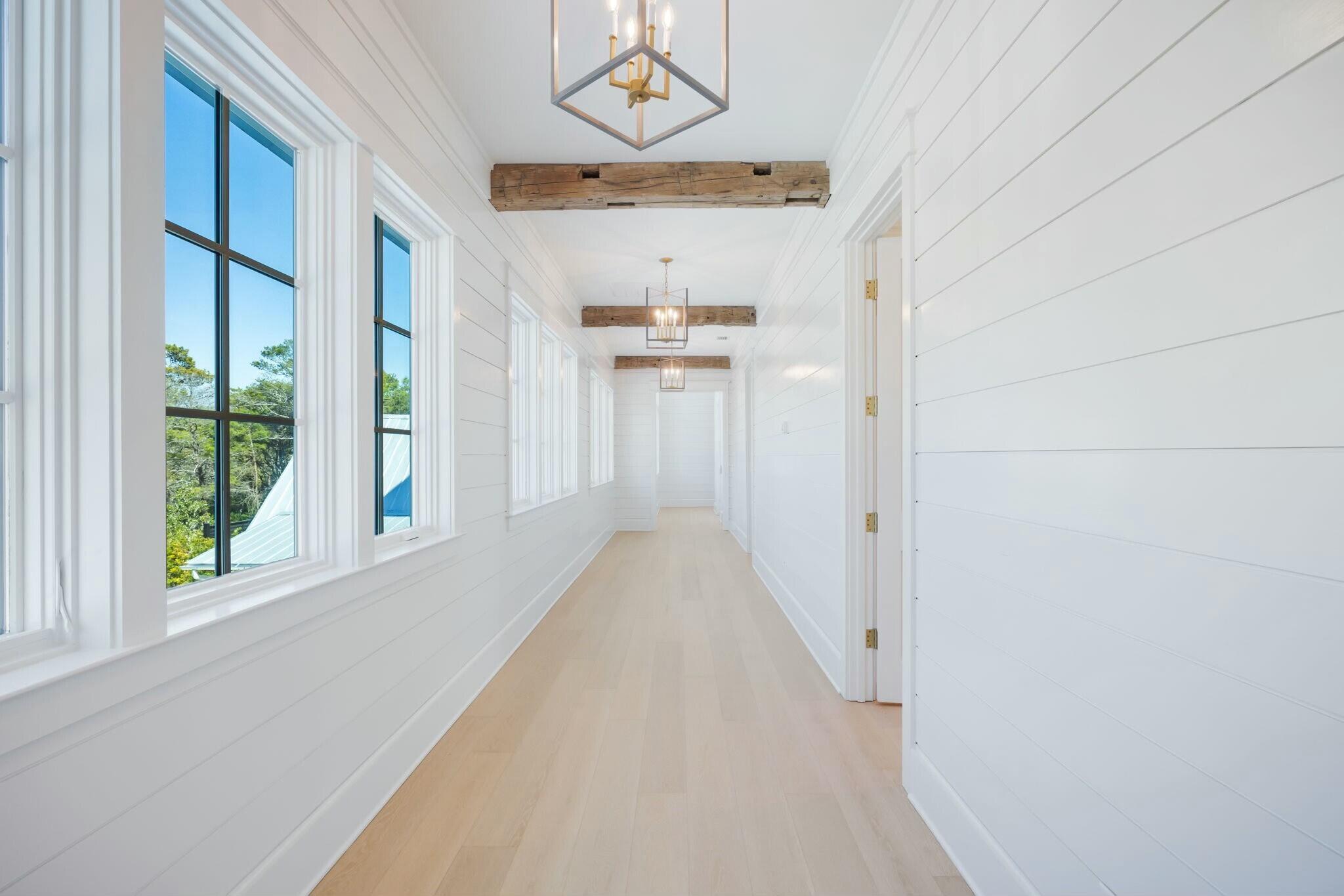 40 Whispering Wind Way Santa Rosa Beach, FL 32459 - Photo 66 of 86 a view of a hallway with wooden floor and a chandelier