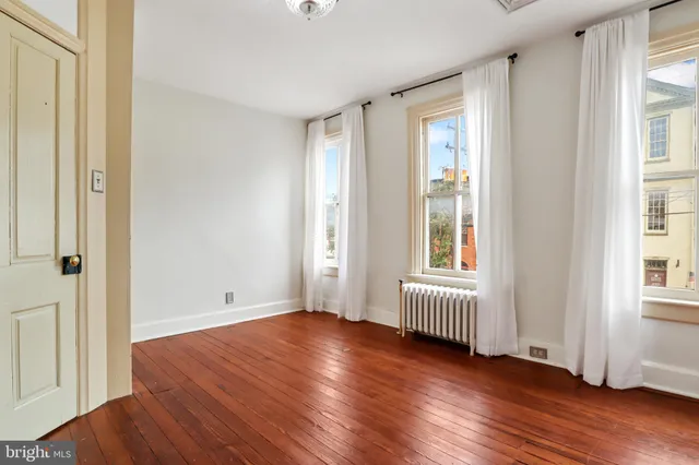 a view of a room with wooden floor and a ceiling fan