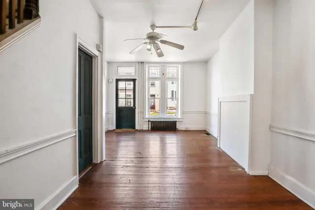 an empty room with wooden floor fireplace and windows